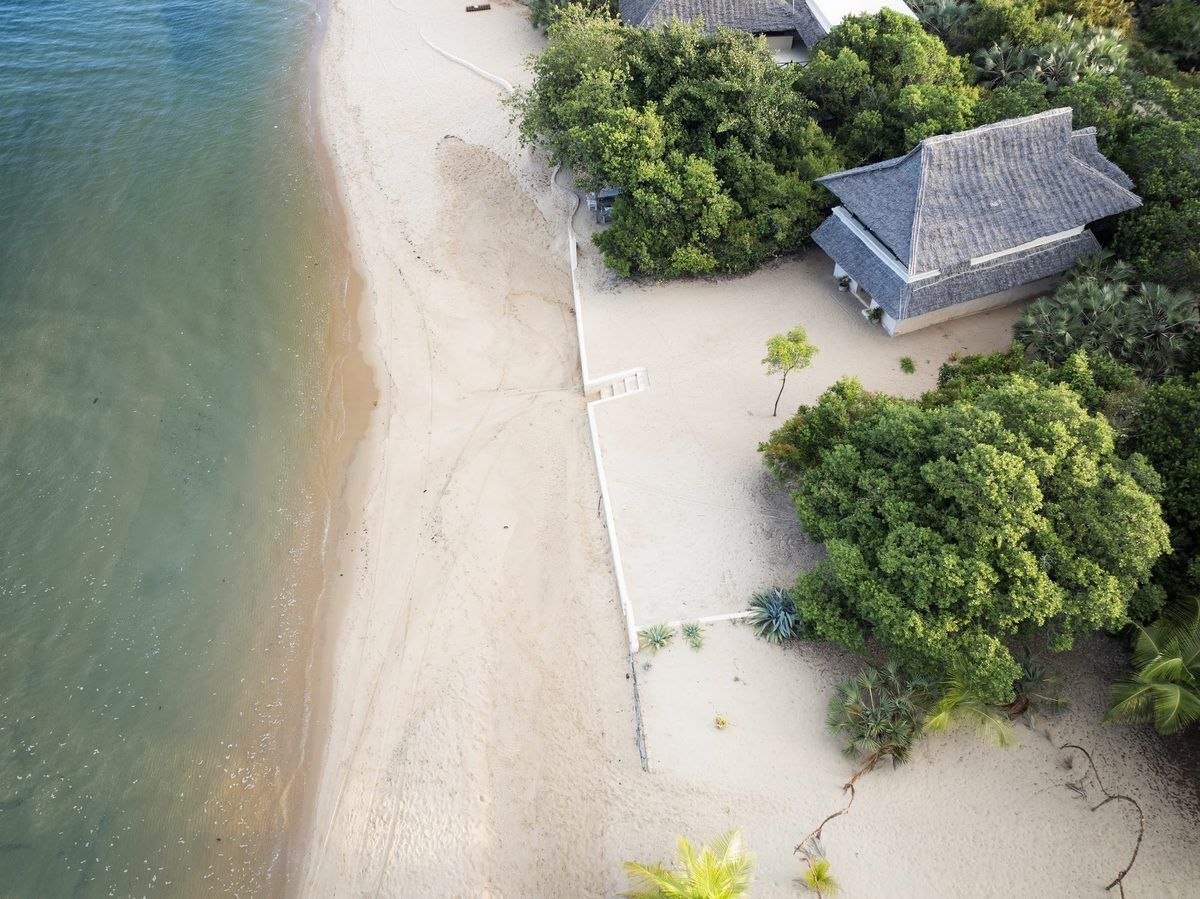 Aerial view of a thatched beachfront cabana at The Cabanas Lamu, set among coastal trees on Kizingoni Beach