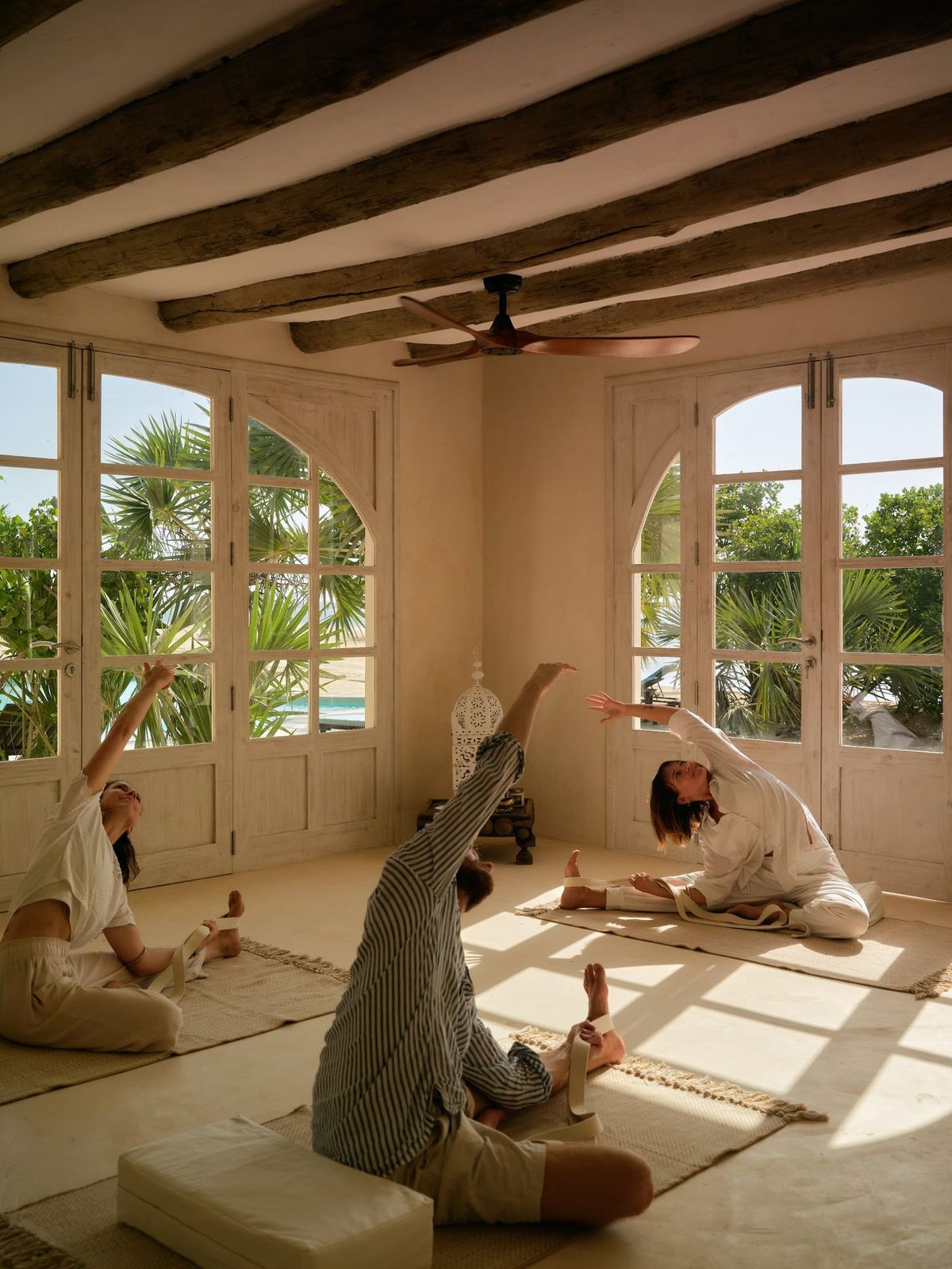 Yoga in white linen, cobra pose by an open Lamu door at the studio