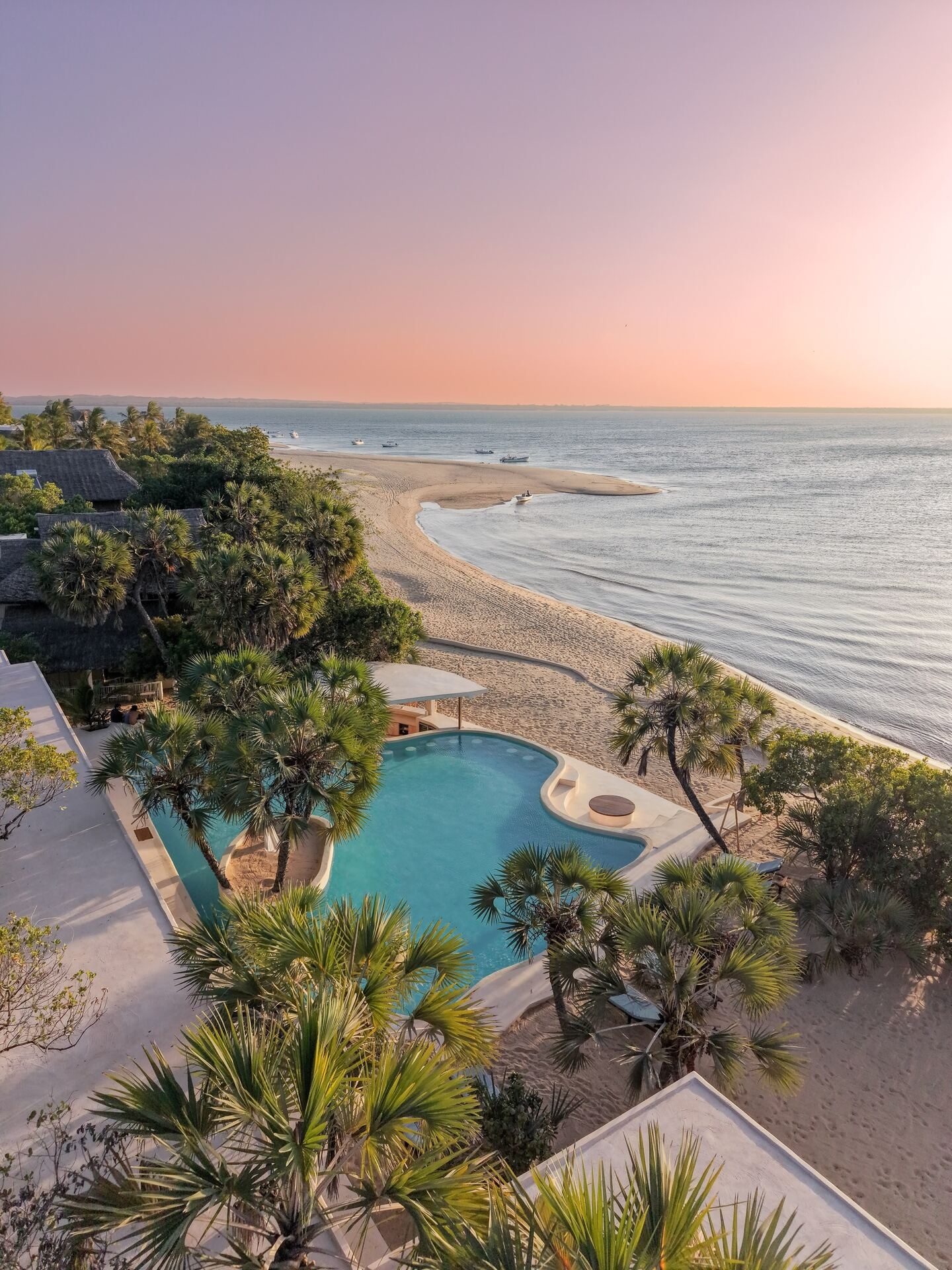 Aerial view of The Cabanas Lamu at golden hour, pool, palm-shaded beach and dhows on Kizingoni Beach, Lamu Island