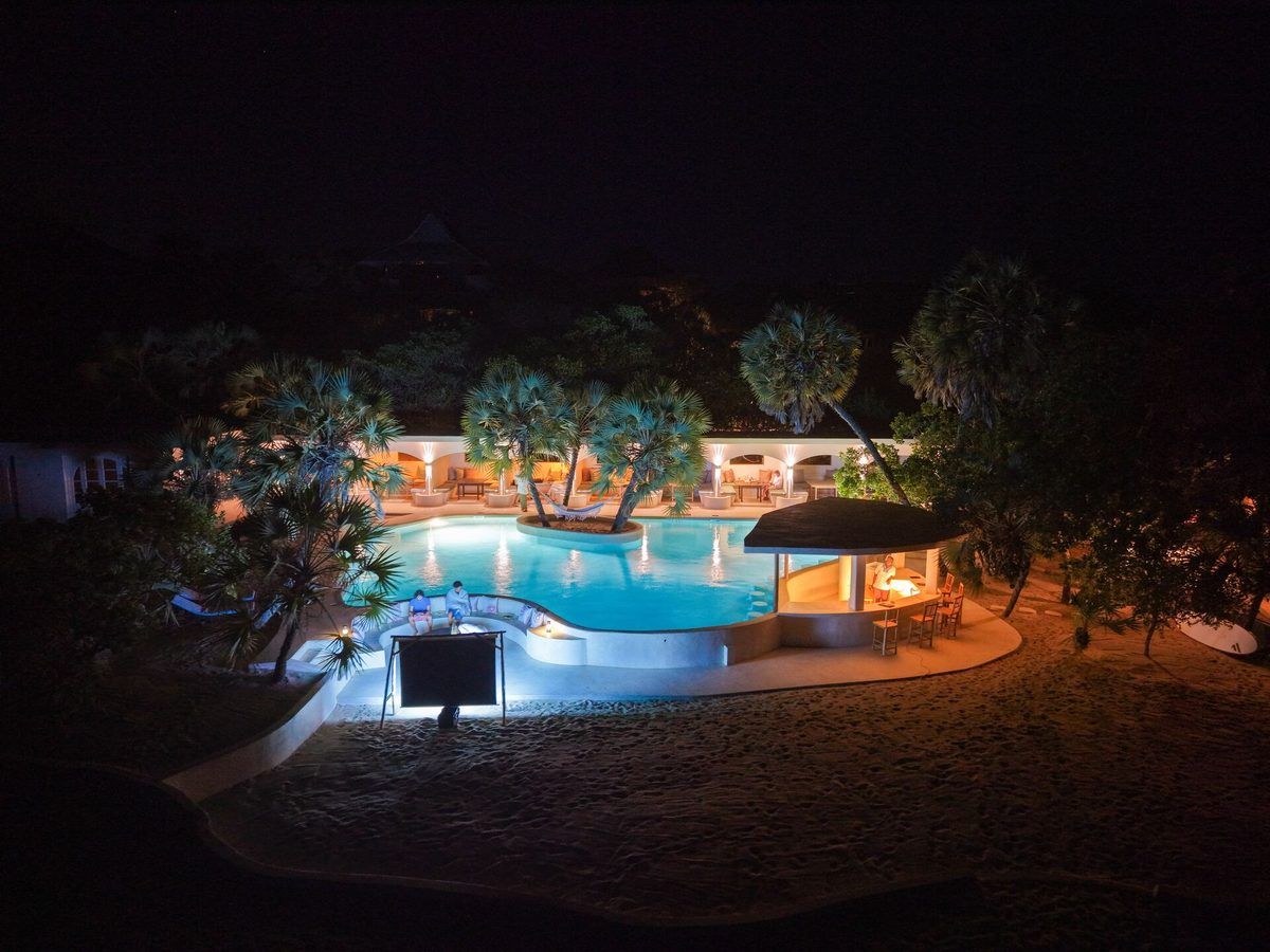 Aerial view of the lit central pool and arched colonnade at The Cabanas Lamu after dusk