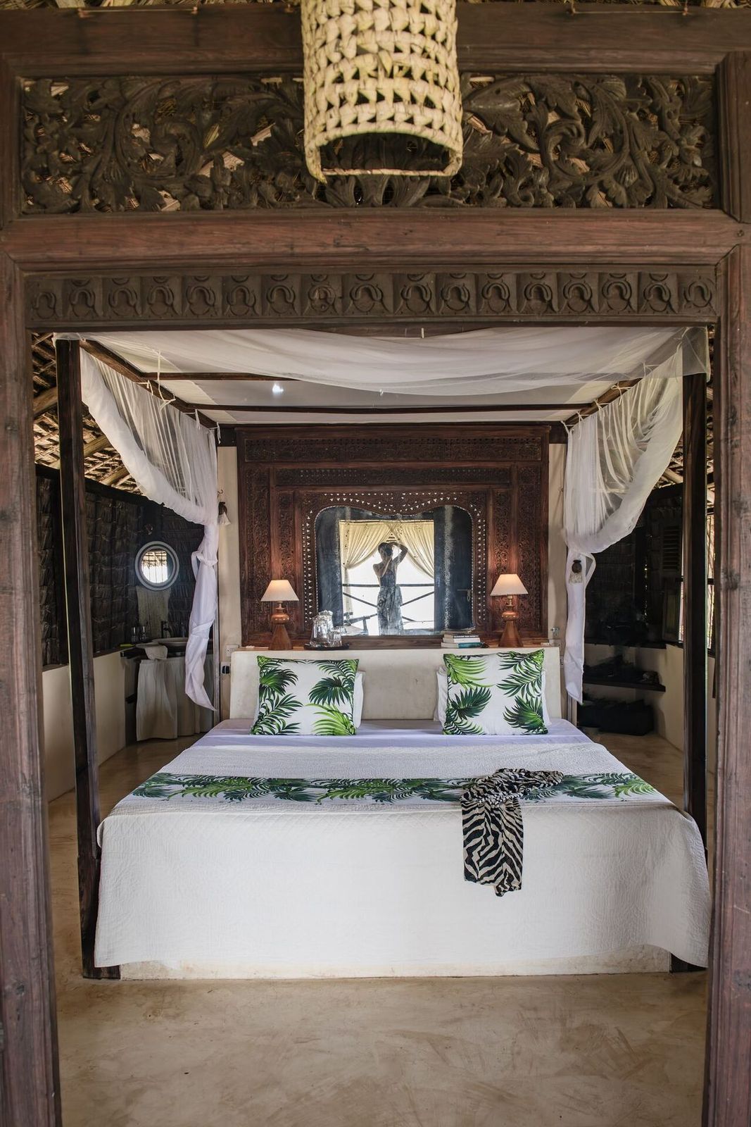 Lōkahi cabana — netted four-poster bed framed by a carved Lamu doorway in soft daylight