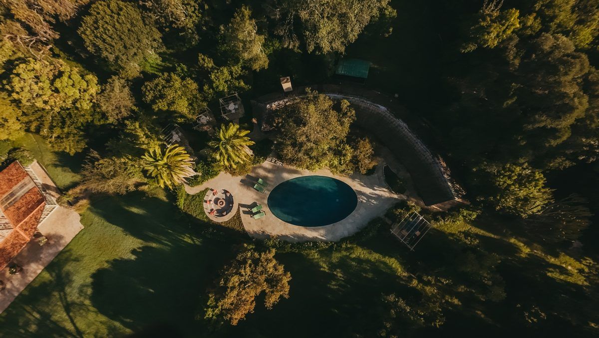 Aerial view of the circular swimming pool tucked into the indigenous forest at Mukima Manor