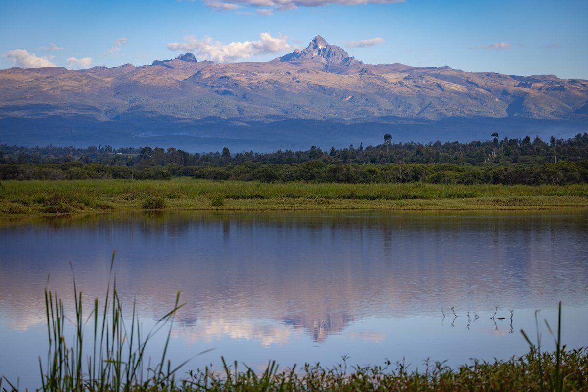 Mt Kenya peak rising above the foothills, mirrored in the private lake at Mukima Manor